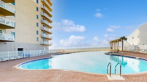A swimming pool with a brick deck, surrounded by a white fence and palm trees. - 22nd-floor beachfront condo with Gulf views, hot tub, pools, sauna, gym, balcony (Panama City Beach)