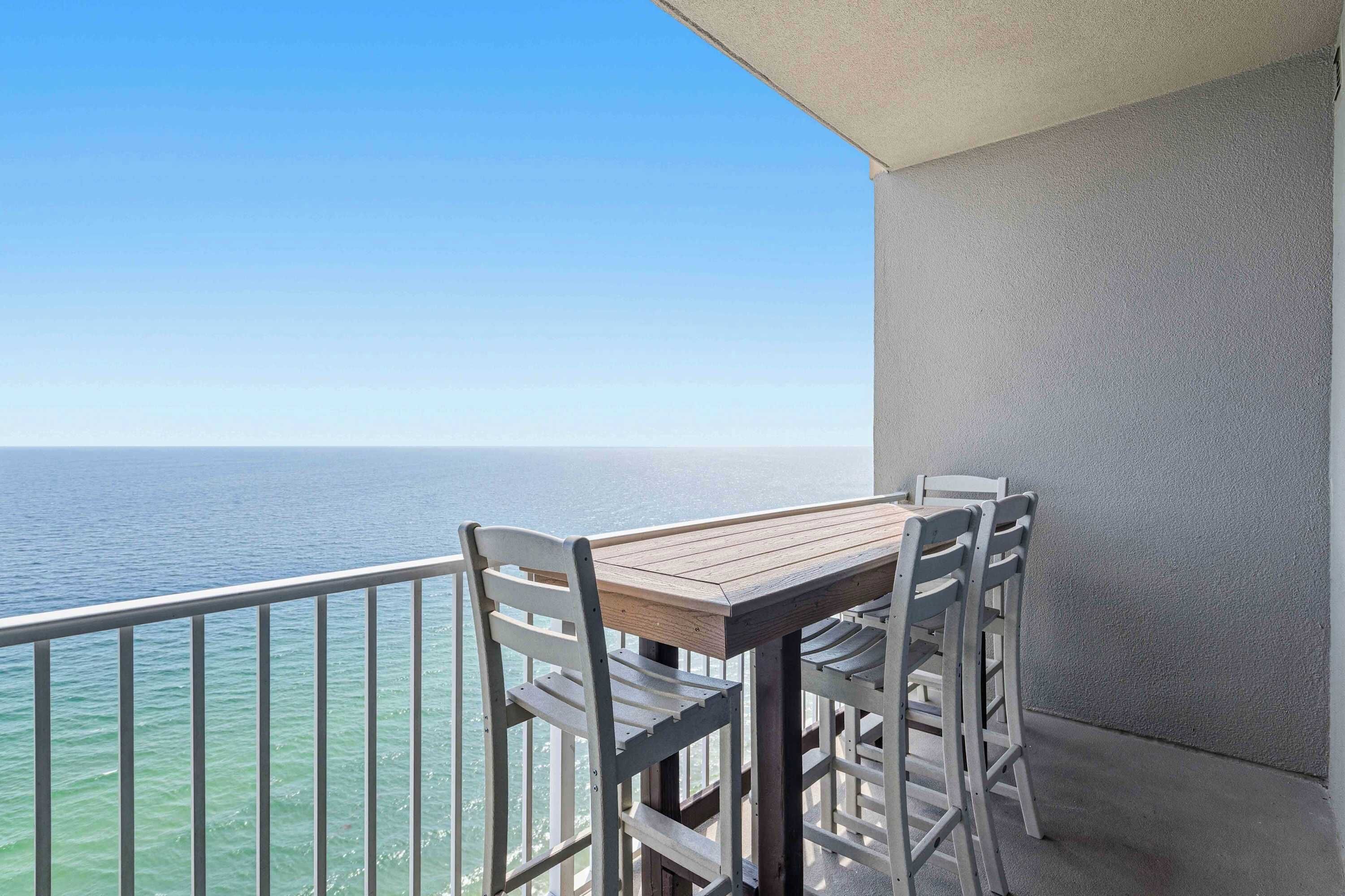 A balcony with a table and chairs, overlooking a body of water.