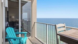 A balcony with a view of the ocean, a table, and two chairs. - Waterfront condo with furnished balcony, hot tub, pools & gym (Panama City Beach)