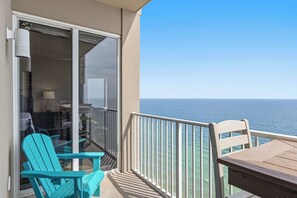 A balcony with a view of the ocean, a table, and two chairs. - Waterfront condo with furnished balcony, hot tub, pools & gym (Panama City Beach)