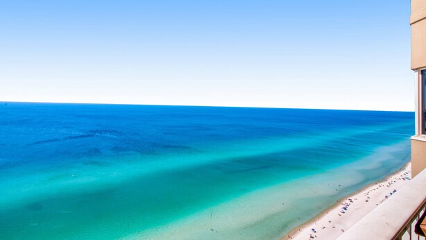 A balcony with a view of a beach and ocean. - Waterfront condo with furnished balcony, hot tub, pools & gym (Panama City Beach)