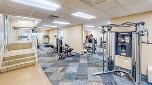 A gym with various exercise equipment, a staircase, and a patterned carpet. - Exquisite Gulf front condo w/shared pool, hot tub &, gym/Roman spa on-site (Panama City Beach)