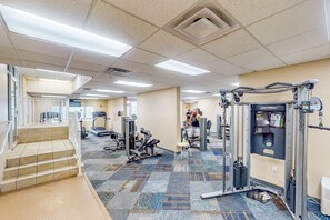 Ein Fitnessraum mit unterschiedlichen Trainingsgeräten, einer Treppe und einem gemusterten Teppich.