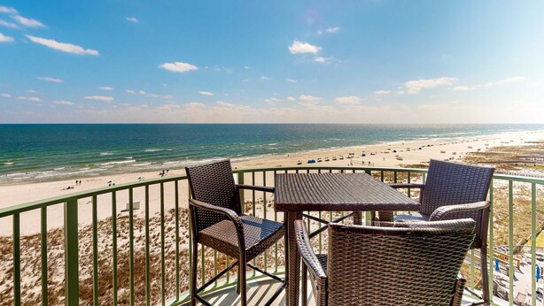 Ein Balkon mit Korbmöbeln und Blick auf einen Strand.