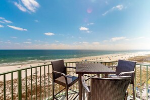 Een balkon met rieten meubilair met uitzicht op een strand.