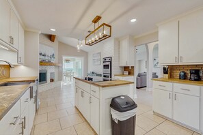 A modern kitchen with white cabinetry, a central island, and a built-in oven. - Waterfront Private Dock & Hot Tub, Pet Friendly HOME with Beach/Ocean views, Grill & Wifi (Pensacola)