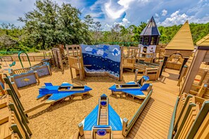 A playground with wooden structures, slides, and a sandy play area. - Modern home with large backyard, deck, and close to the beach (Perdido Key)