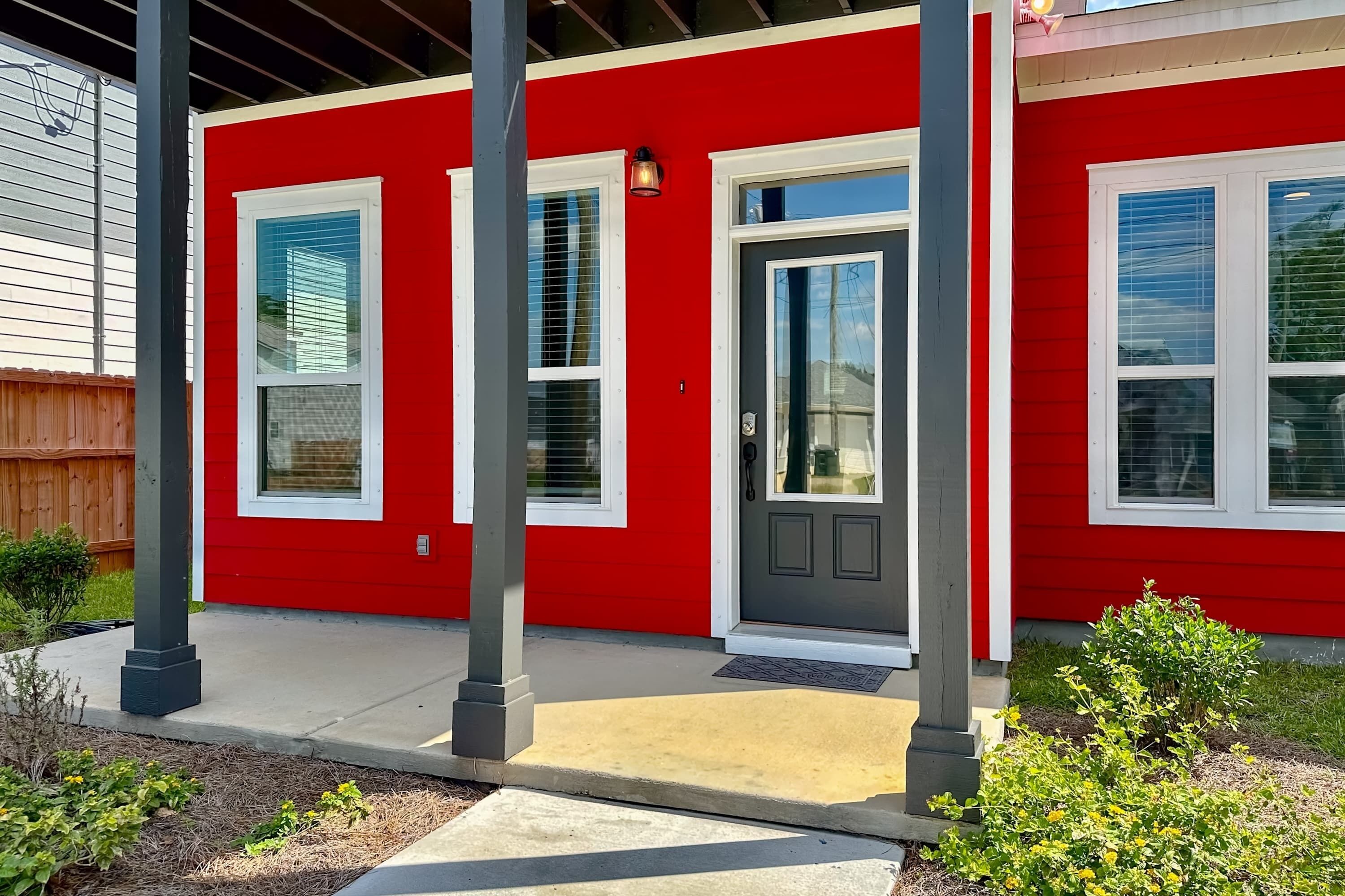 A red house with a gray door and white-framed windows.