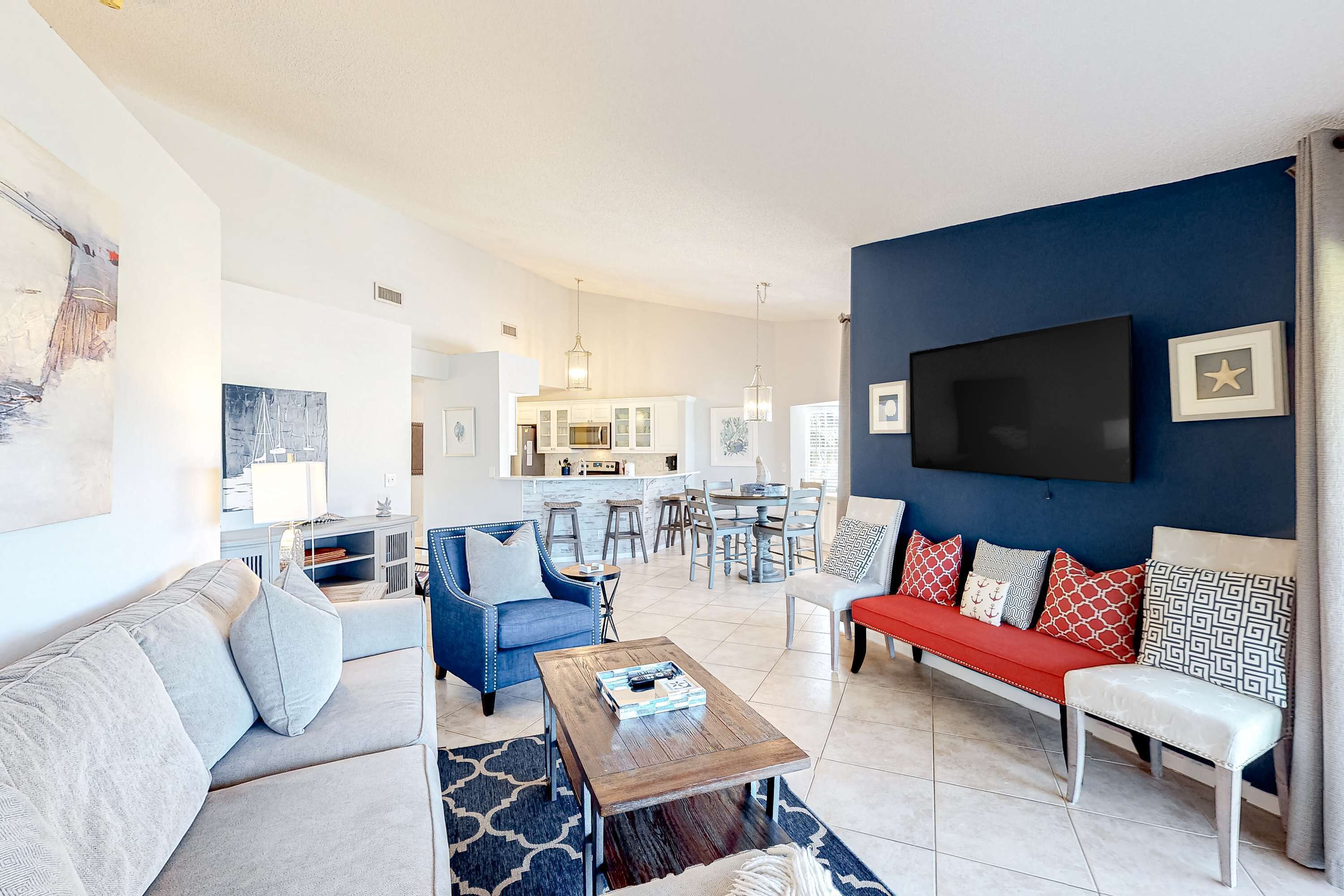 Ein modernes Wohnzimmer mit einem blauen, einem roten und einem grauen Sofa. In der Mitte steht ein Couchtisch aus Holz.