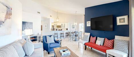 Ein modernes Wohnzimmer mit einem blauen, einem roten und einem grauen Sofa. In der Mitte steht ein Couchtisch aus Holz.