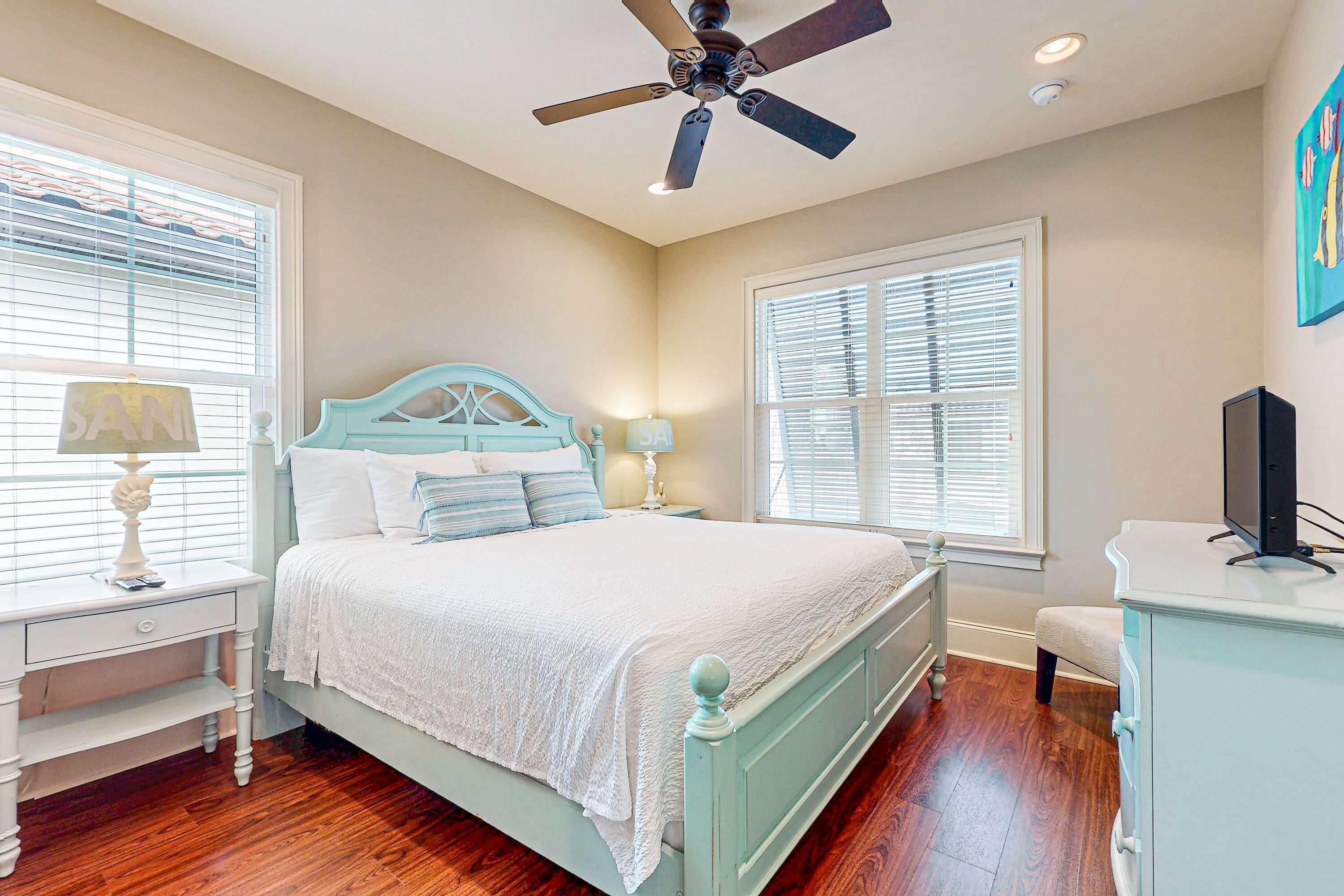 A bedroom with a bed, nightstands, a ceiling fan, and a television.