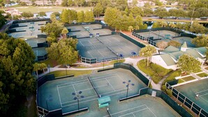 Ilmakuva urheilukeskuksesta, jossa on useita tenniskenttää, ja jonka ympärillä on puita ja asuinrakennuksia.