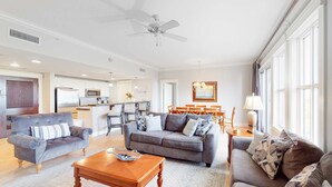 Ein geräumiges Wohnzimmer mit grauem Sofa, einem Holztisch und einem Deckenventilator.