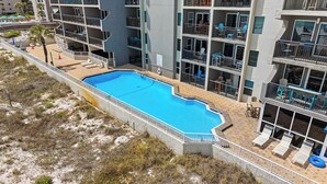Un hotel de varios pisos con piscina, balcones con asientos exteriores y una zona de playa.