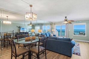 A spacious living area with a large glass dining table, comfortable seating, and a view of the ocean. - Seventh-floor oceanfront condo with pool access, ocean view, & central AC (Fort Walton Beach)