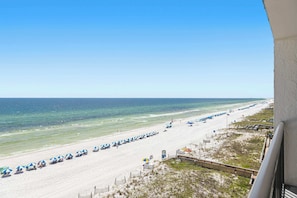 A beach with rows of umbrellas and chairs, a clear sky, and the ocean. - Seventh-floor oceanfront condo with pool access, ocean view, & central AC (Fort Walton Beach)