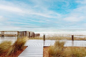 Ein Holzsteg führt zu einem Strand, an dem ein Schild 'Schwimmen verboten' steht.