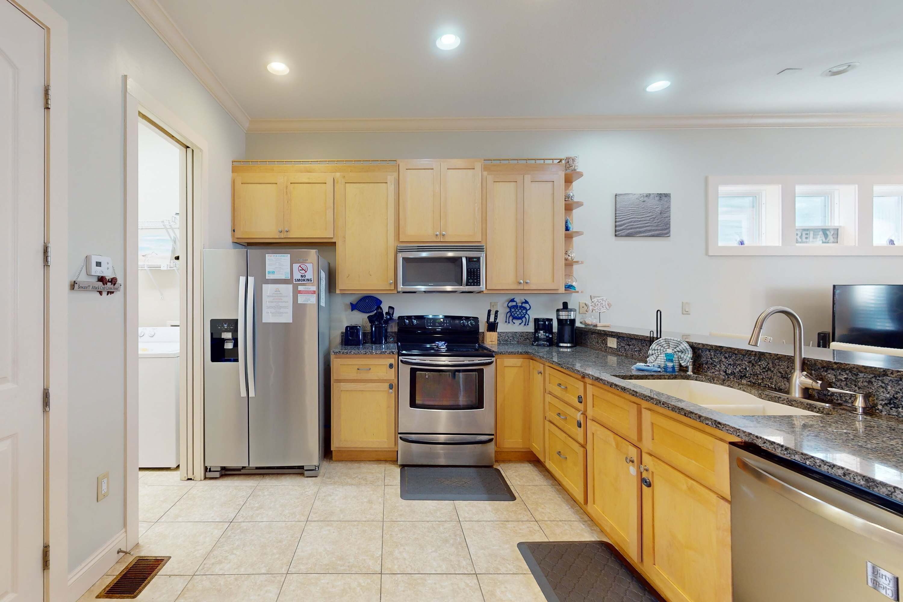 A modern kitchen with wooden cabinets, stainless steel appliances, a granite countertop, and a built-in dishwasher.