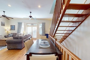 A spacious living area with a wooden dining table, a sofa, and a ceiling fan. - 3-story, dog-friendly home with pool & balcony - walk to beach (Panama City Beach)