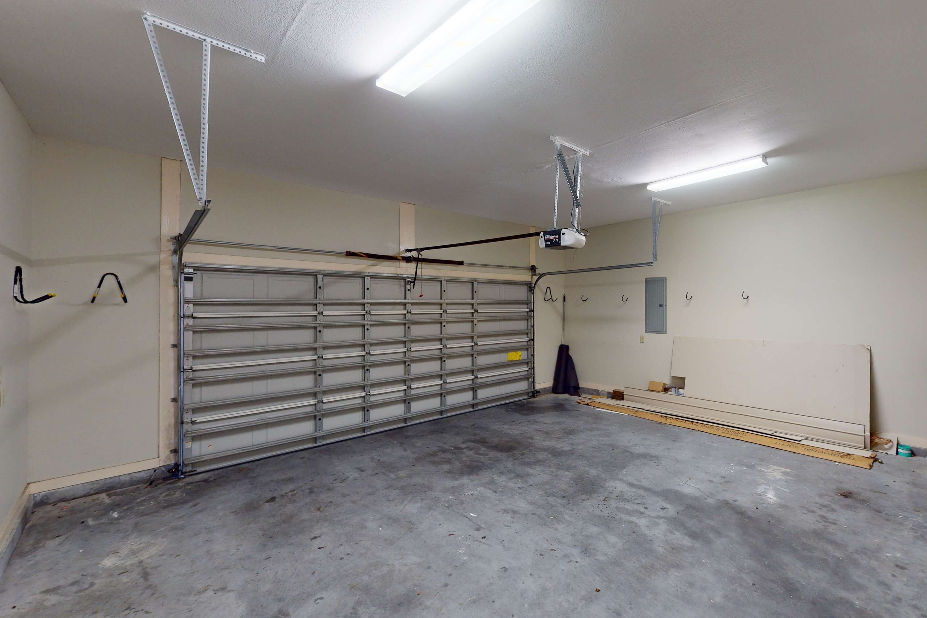 A garage with a closed metal door, fluorescent lighting, and a concrete floor.