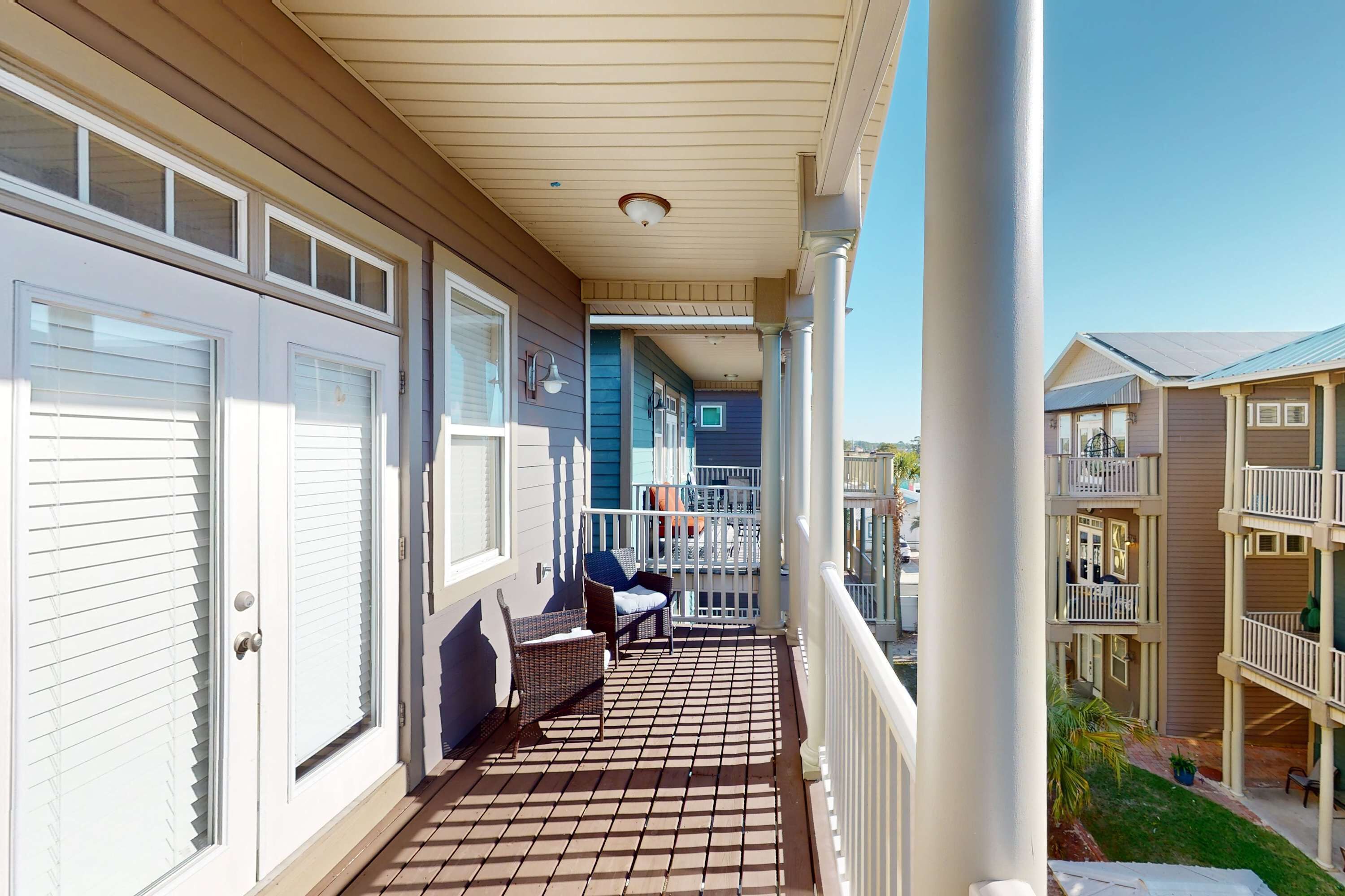 A covered balcony with a tiled floor, white railings, and a view of adjacent buildings.