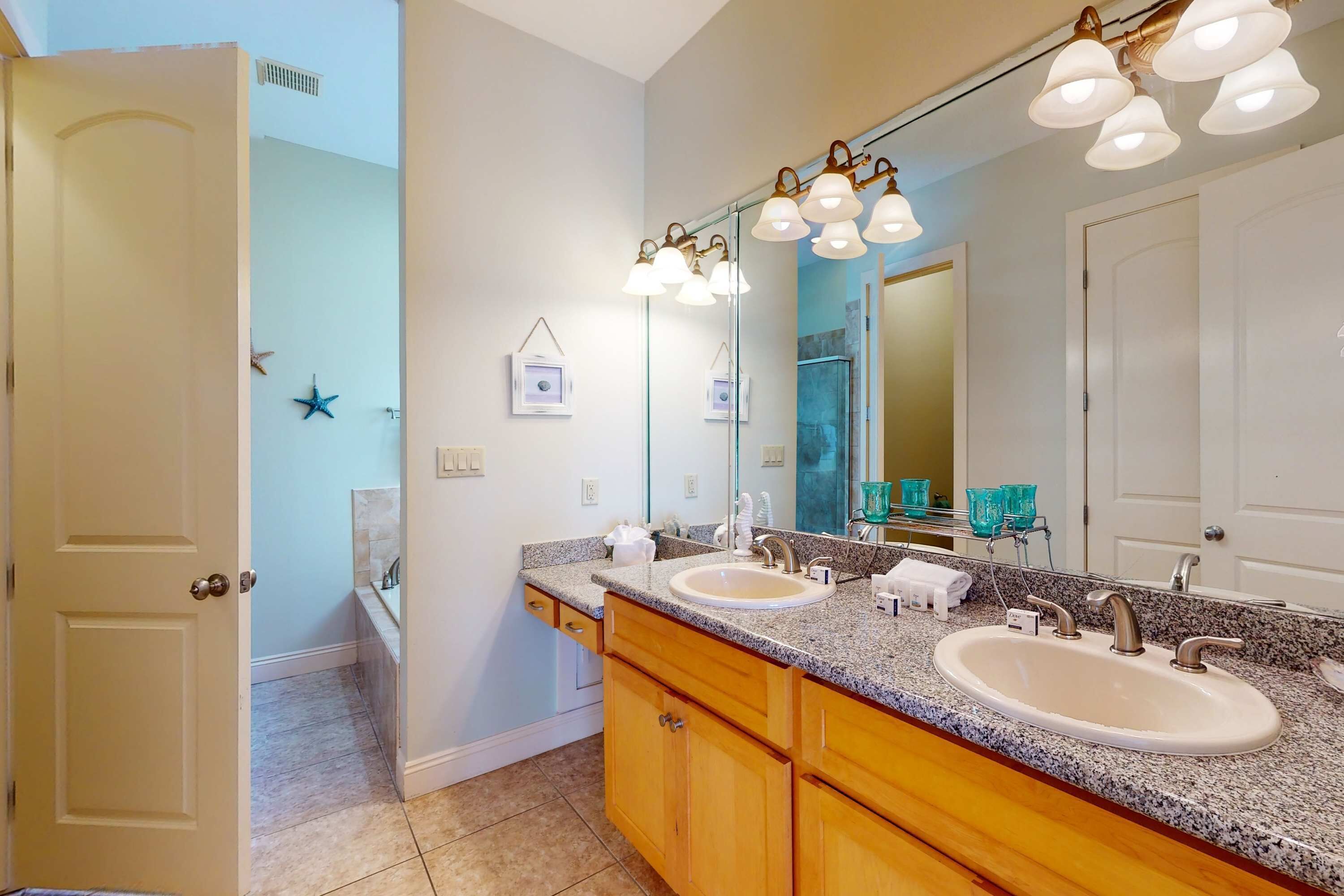 A bathroom with two sinks, wooden cabinets, a large mirror, and a ceiling light fixture.