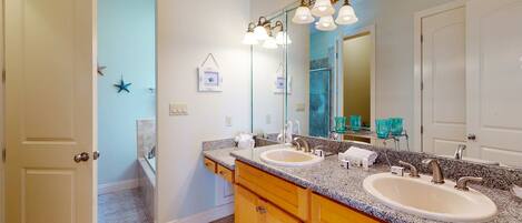 A bathroom with two sinks, wooden cabinets, a large mirror, and a ceiling light fixture.