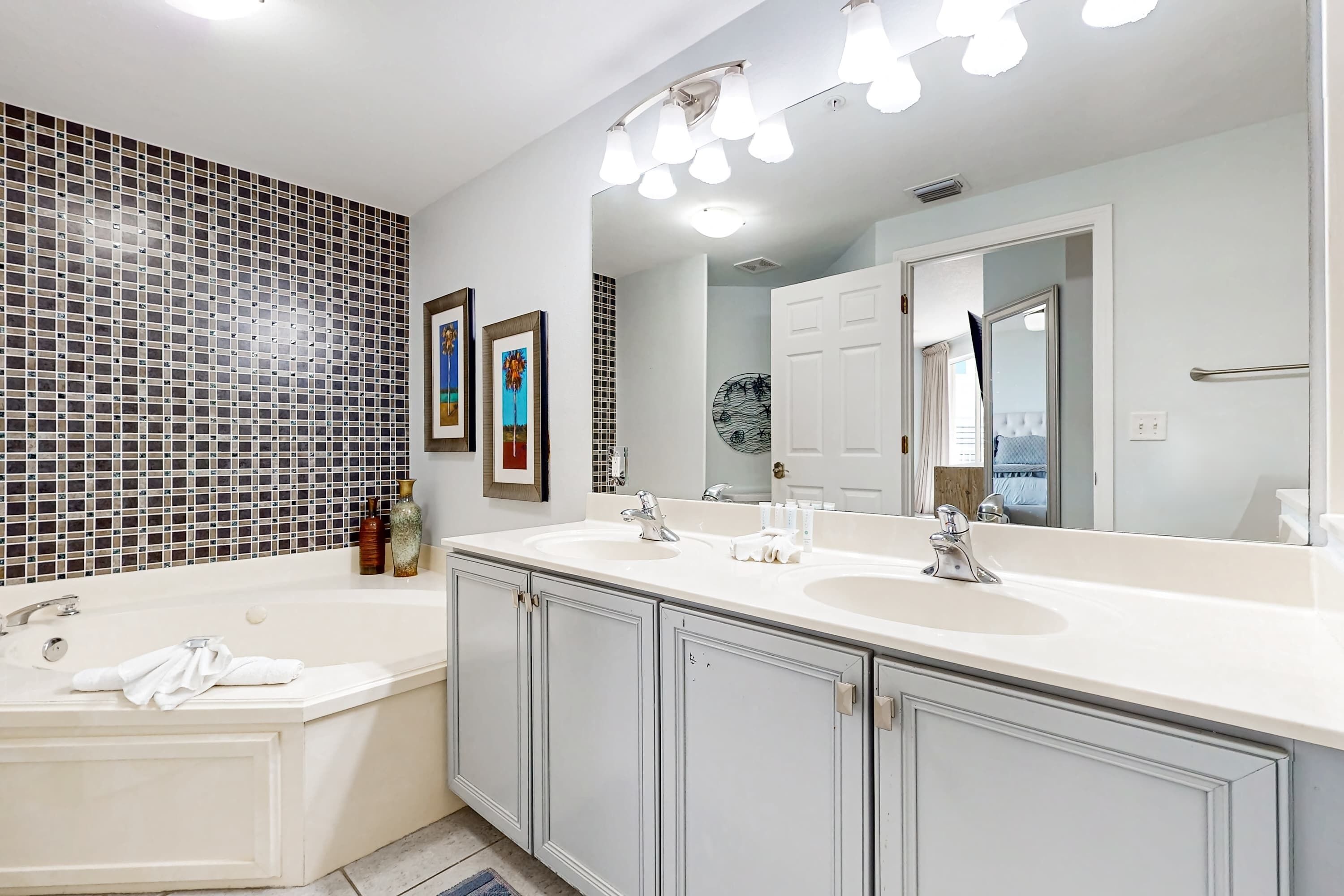 A modern bathroom with a large bathtub, two sinks, and a large mirror.