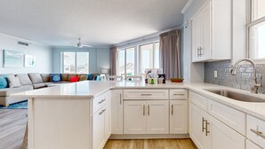 Una cocina moderna con armarios blancos, una isla grande y una zona de comedor con sofá y sillas.