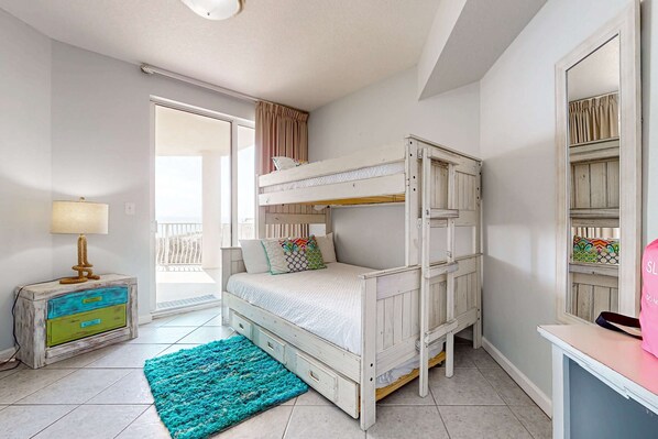 A bedroom with a bunk bed, a bedside table with a lamp, a dresser, and a large mirror. - Ground floor beachfront condo with shared pool and beach access (Santa Rosa Beach)