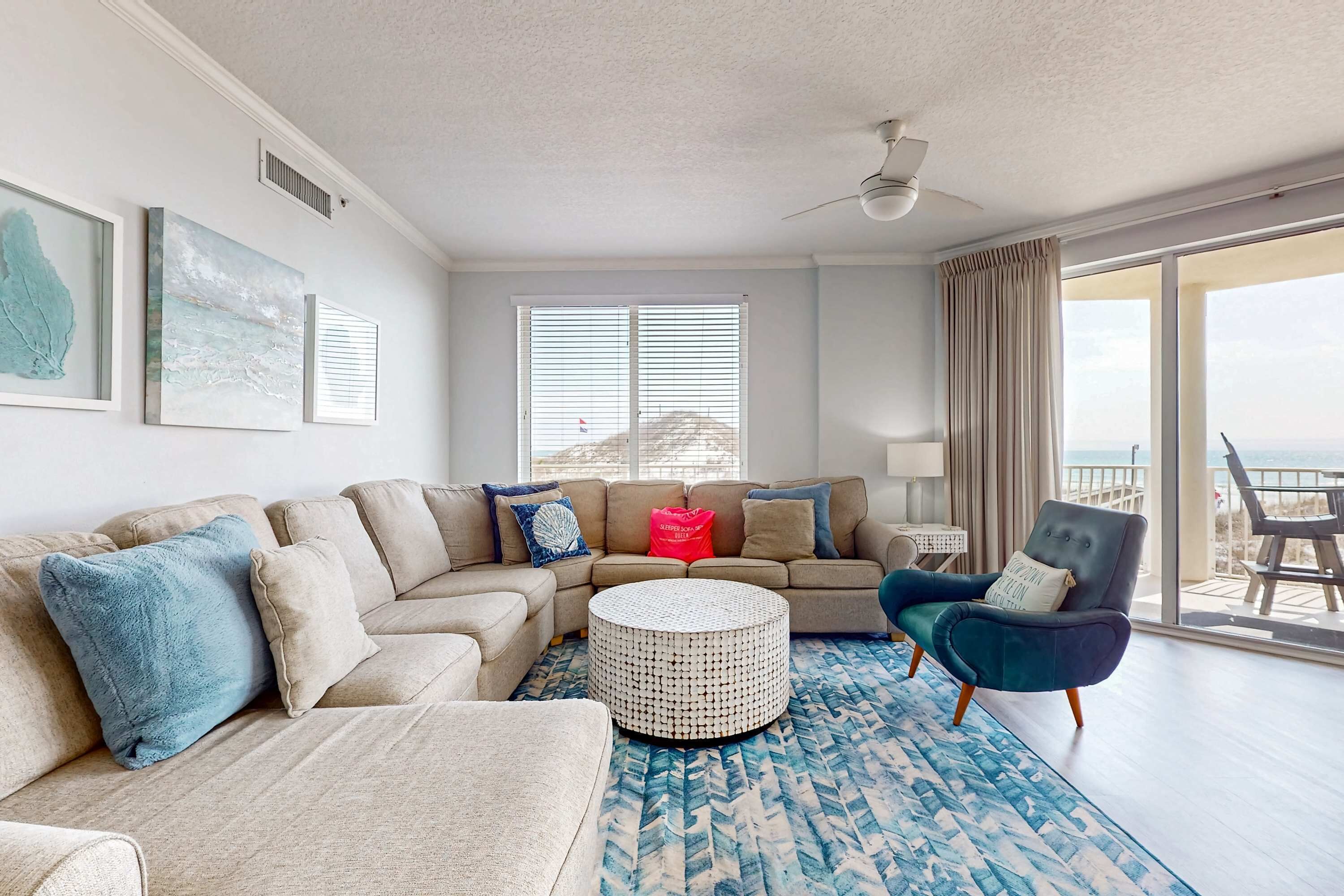 A living room with a beige sectional sofa, a round coffee table, and a blue patterned rug.