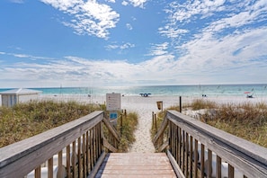 A wooden boardwalk leading to a beach with a clear sky and calm sea. - Ground floor beachfront condo with shared pool and beach access (Santa Rosa Beach)