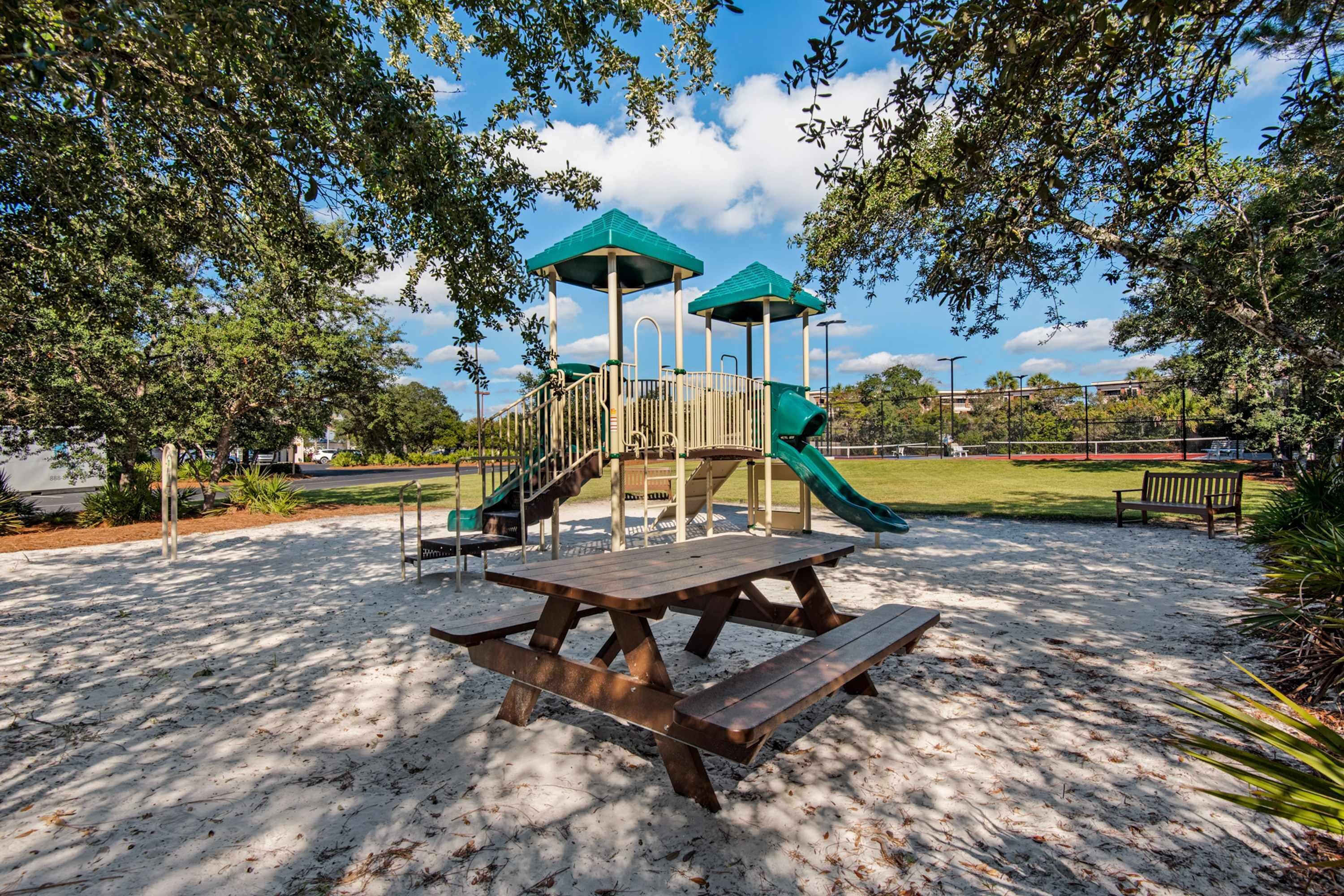 A playground with a slide, picnic table, and covered seating area.