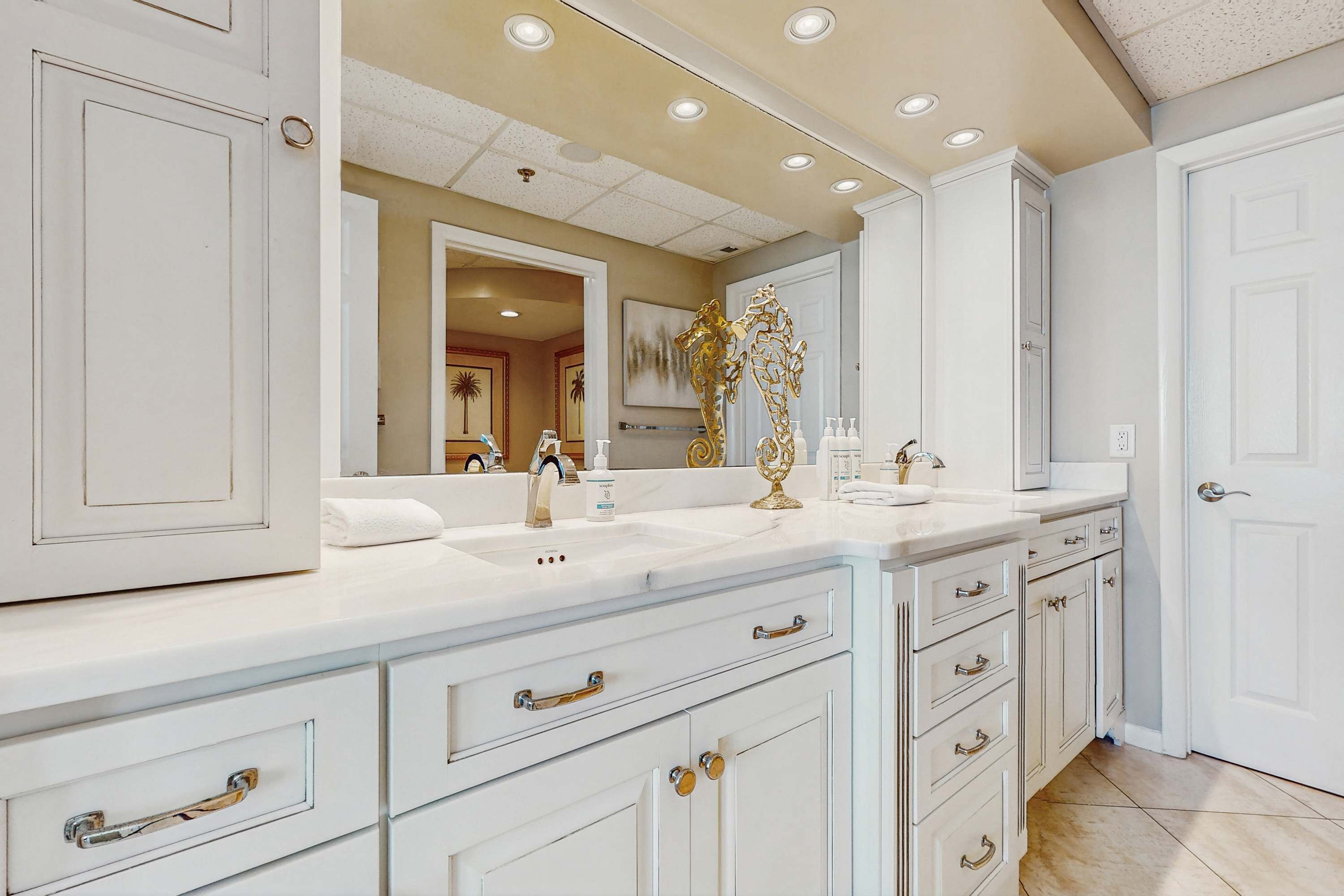 A bathroom with a white vanity, double sink, and a large mirror.