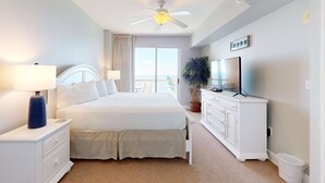 Un dormitorio con cama, mesita de noche, cómoda, televisor y ventilador de techo.