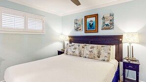 Una camera da letto con un letto, due comodini, una ventola a soffitto e decorazioni a parete.