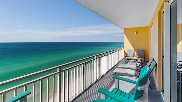 A balcony with a view of the ocean, a table with chairs, and a yellow wall. - 16th-floor oceanfront condo with ocean view, WiFi, and hot tub/pool (Panama City Beach)