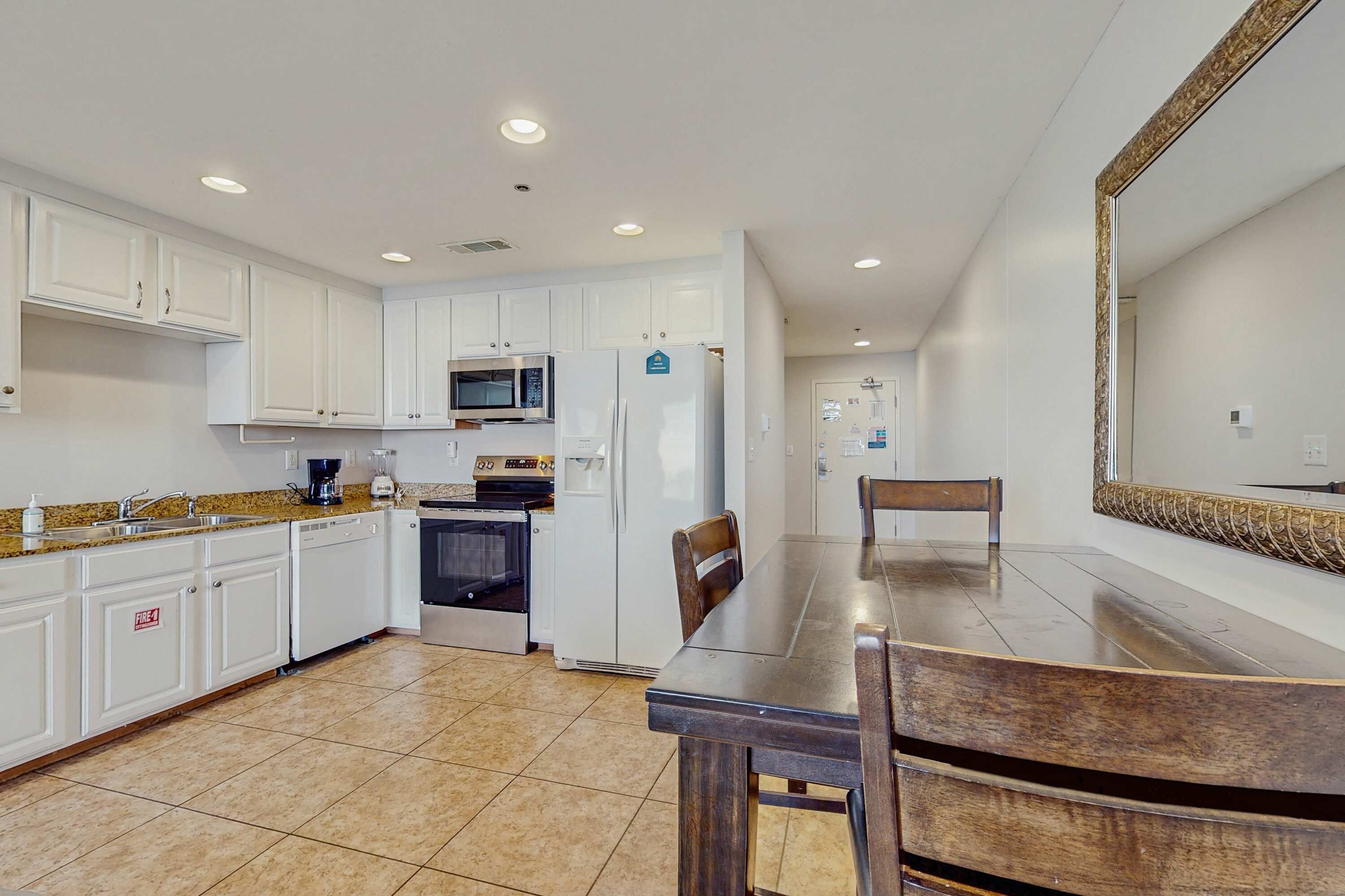 A modern kitchen with white cabinets, a microwave, a refrigerator, and a dining table with chairs.