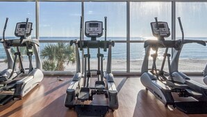 A gym with cardio machines and a view of the beach. - 16th-floor oceanfront condo with ocean view, WiFi, and hot tub/pool (Panama City Beach)