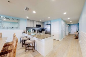Eine moderne Küche mit weißen Schränken, einer Granit-Arbeitsplatte und einer eingebauten Mikrowelle.