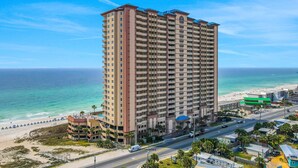 Un hotel di grattacielo con diverse altezze, vista sulla spiaggia e un'area parcheggio.