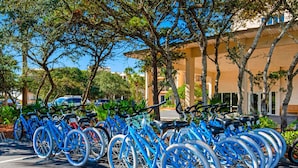 A row of blue bicycles parked in a lot with trees and a building in the background. - Gorgeous home with tennis, pickleball, pool & hot tub - steps from the beach (Seacrest)