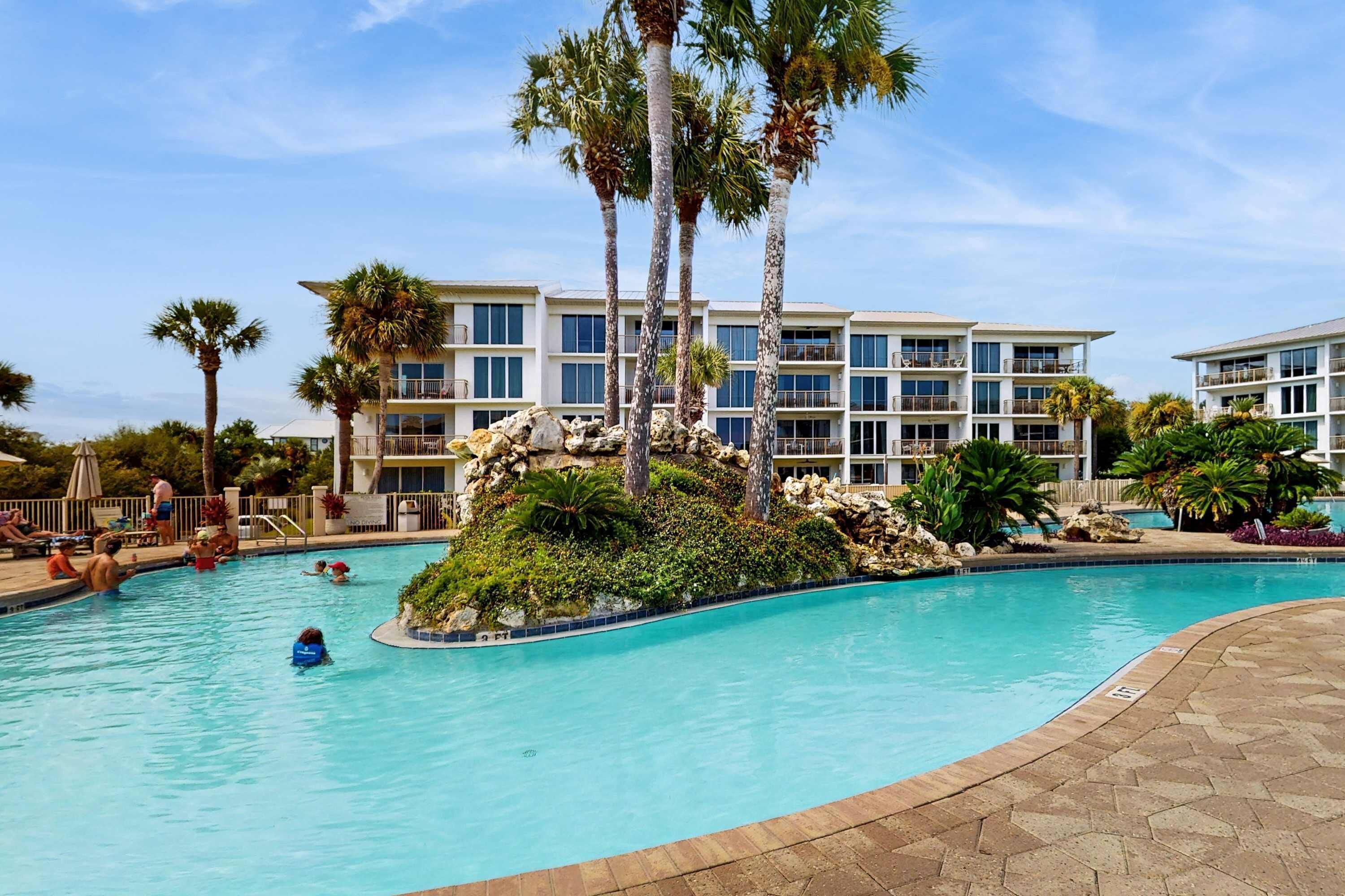 A swimming pool with palm trees and a building in the background.