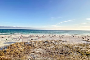 A beach with people, a small structure, and the ocean. - Second-Floor Gulf Front Condo with Shared Pool & Boardwalk in the Heart of Destin (Destin)