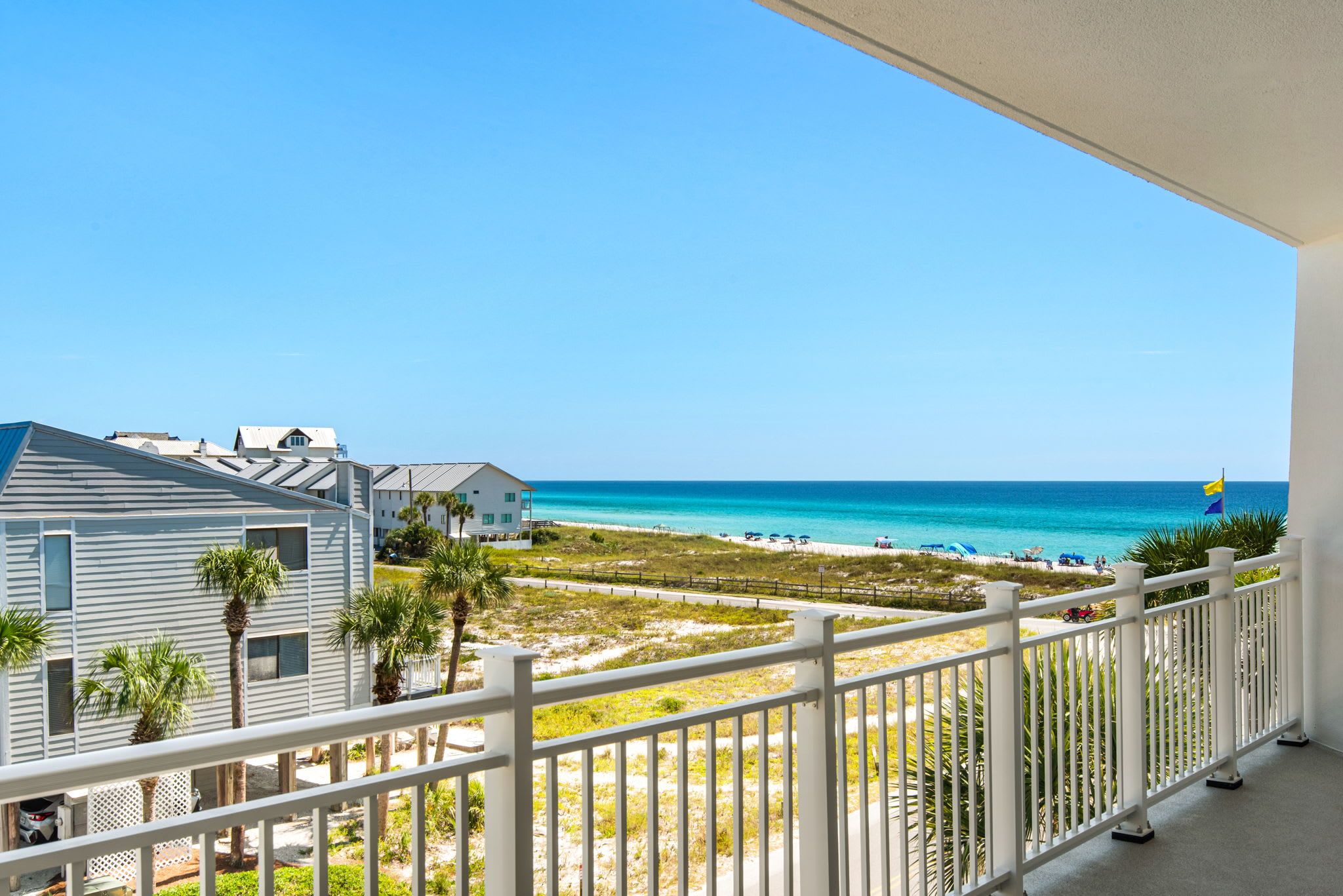 A balcony with a view of the beach and ocean.