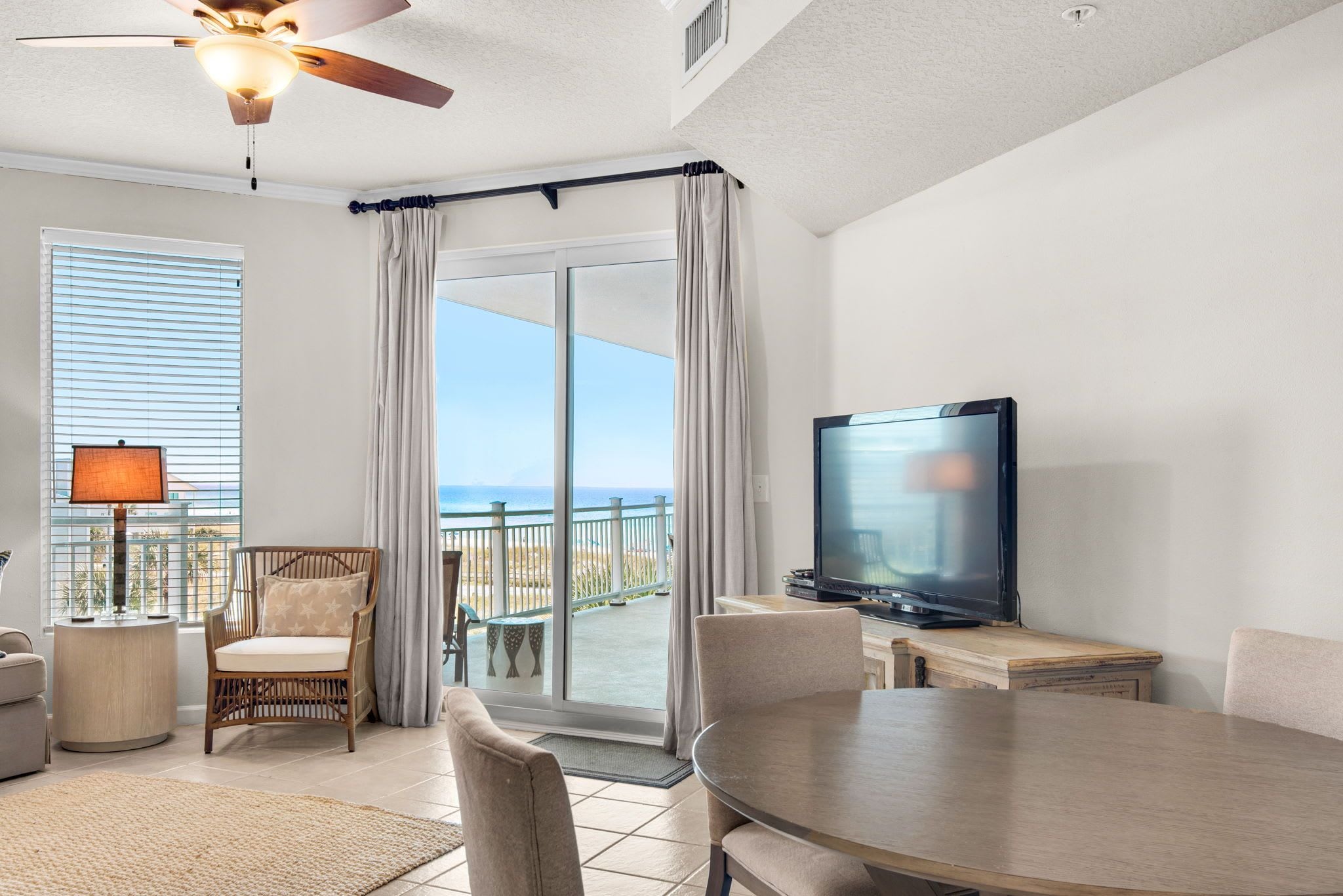 A hotel room with a balcony, a television, a dining table, and a chair.