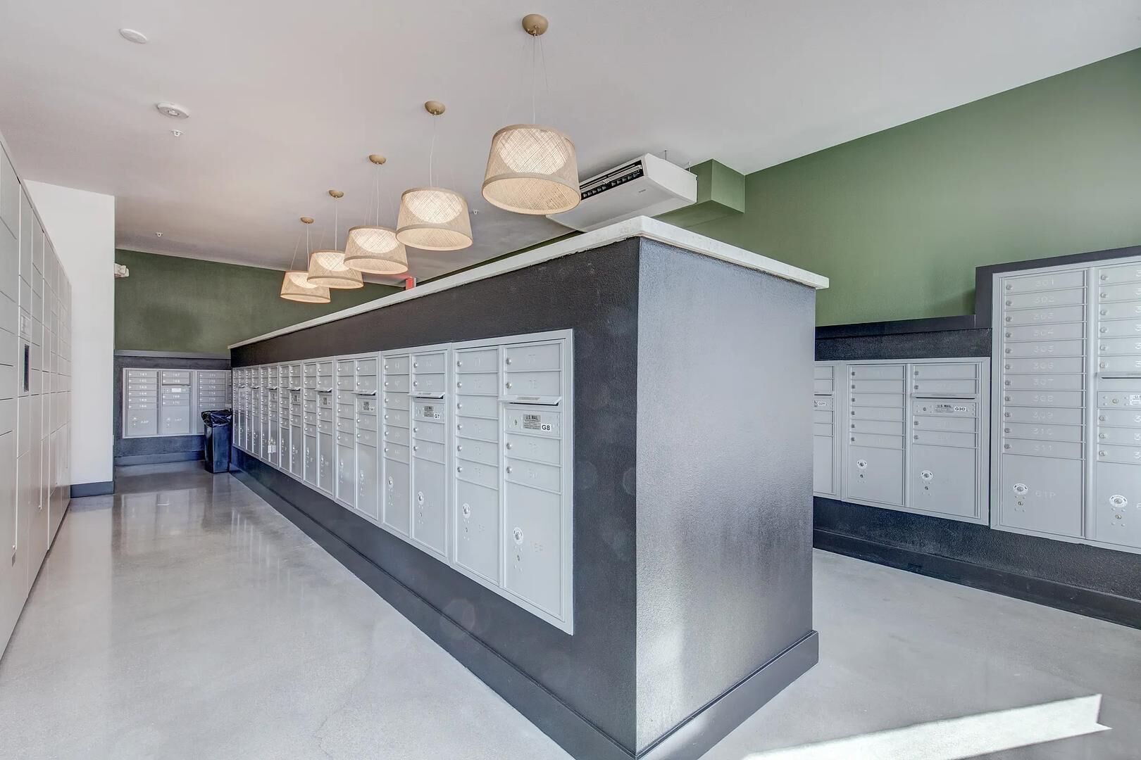 A modern lobby with a row of lockers, a reception desk, and pendant lighting.