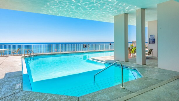 An indoor swimming pool with clear blue water, a view of the ocean, and a white railing. - Inviting Gulf-front condo In Perdido Key with waterfront pool/hot tub and oceanfront balcony (Perdido Key)