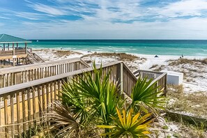 A beach with a wooden boardwalk, a beach hut, and a view of the ocean. - Family-friendly Gulf view condo with beach chair & umbrella, shared pool,hot tub (Miramar Beach)