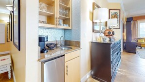 A modern kitchen with a built-in dishwasher, a sink, and a coffee machine. There is a cabinet with glassware and a decorative lamp. - Inviting Gulf-front condo In Perdido Key with waterfront pool/hot tub and oceanfront balcony (Perdido Key)